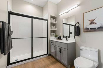 a bathroom with a toilet sink and shower with a glass door